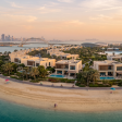 Aerial view of Hudayriyat Island in Abu Dhabi at golden hour, showing Modon villa communities, coastline, sports facilities, and the Abu Dhabi skyline — a 2026 investor guide.