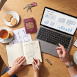 Overhead flat-lay of a British couple’s kitchen table during a Dubai property planning session — laptop, passport, notebook, tea, and Dubai map