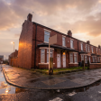 Row of British terraced houses with a for-sale board, representing UK landlords deciding whether to sell